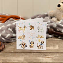  Greeting card with illustrations of dogs and text 'It's pawty time' on a wooden surface.