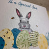 Blank Easter Card for young son; this card features a cute bunny peaking out from behind some colourful blue, green, and yellow Easter eggs. The text reads "To a Special Son Happy Easter". 1