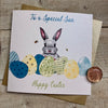 Blank Easter Card for young son; this card features a cute bunny peaking out from behind some colourful blue, green, and yellow Easter eggs. The text reads "To a Special Son Happy Easter".