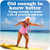 Funny woman's coaster; featuring an old lady, standing on a surfboard in the summer sun; bold white text behind her reads 'old enought o know better, young enough to make a tit of yourself anyway'; by Dean Morris