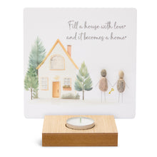  These wood t-light candle holders feature lovely artwork and sentimental messages. The candle burns in front of the printed artwork illuminating the message.&nbsp;

The artwork here depicts a lovely family home and garden with a pebble art family. The message reads Fill a house with love and it becomes a home.