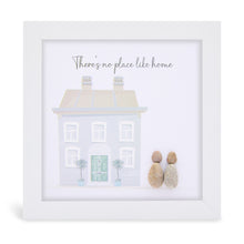  This white shadowbox framed pebble art print features a a beautiful house design as two figures look on. It reads There's no place like home.