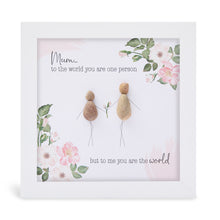  This white shadowbox framed pebble art print features a mother and daughter exchanging flowers and has a floral motif design.&nbsp;It reads Mum to the world you are one person but to me you are the world.