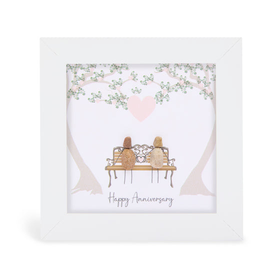These small white shadow box frame gifts are made with a 4-inch white shadow box frame with a plexiglass insert, helping it be less fragile in the post and around the home. You can also easily take them apart to clean the inside of the glass or frame if you need to. They come individually boxed for added protection during shipping.

This white shadowbox framed pebble art features 2 people sittinng on a park bench. It reads Happy Anniverysary