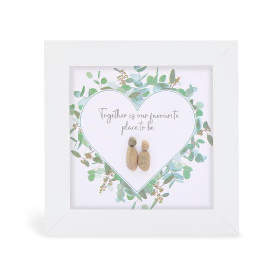 These small white shadow box frame gifts are made with a 4-inch white shadow box frame with a plexiglass insert, helping it be less fragile in the post and around the home. You can also easily take them apart to clean the inside of the glass or frame if you need to. They come individually boxed for added protection during shipping.

This white shadowbox framed pebble art print a wild greenery heart design with 2 people standing close inside.&nbsp;It reads Together is our favourite place to be.