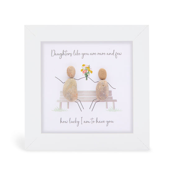 These small white shadow box frame gifts are made with a 4-inch white shadow box frame with a plexiglass insert, helping it be less fragile in the post and around the home. You can also easily take them apart to clean the inside of the glass or frame if you need to. They come individually boxed for added protection during shipping.

This white shadowbox framed pebble art print 2 people sitting on a bench with a bouquet of flowers;It reads Daughters like you are rare and few, how lucky I am to have you
