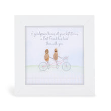  This white box framed pebble art print features two friends riding a bike together with flowers in the basket on the front of the bike. It reads A good friend knows all your best stories, a best friend has lived them with you.
