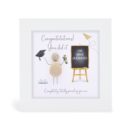 These small white shadow box frame gifts are made with a 4-inch white shadow box frame with a plexiglass insert, helping it be less fragile in the post and around the home. You can also easily take them apart to clean the inside of the glass or frame if you need to.&nbsp;&nbsp;They come individually boxed for added protection during shipping.

This white shadowbox framed pebble art print features a person celebrating graduation. It reads Congratulations! You did it! Completely totally proud of you.