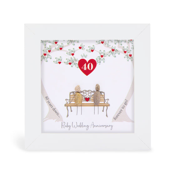 These small white shadow box frame gifts are made with a 4-inch white shadow box frame with a plexiglass insert, helping it be less fragile in the post and around the home. You can also easily take them apart to clean the inside of the glass or frame if you need to.&nbsp; They come individually boxed for added protection during shipping.&nbsp;

This white shadowbox framed pebble art print features 2 people sitting on a bench underneath two trees that are reaching over them. There is a small red heart where 