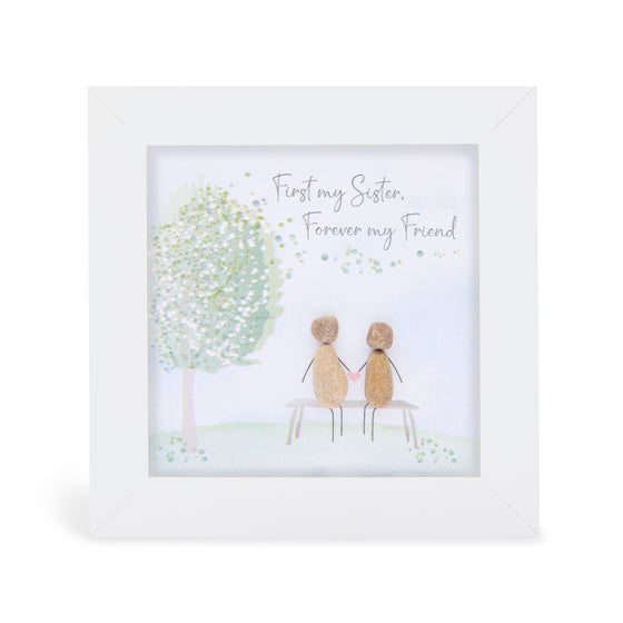 These small white shadow box frame gifts are made with a 4-inch white shadow box frame with a plexiglass insert, helping it be less fragile in the post and around the home. You can also easily take them apart to clean the inside of the glass or frame if you need to. They come individually boxed for added protection during shipping.

This white shadowbox framed pebble art print 2 people sitting in on a bench in a park. It reads First my Sister, Forever my Friend