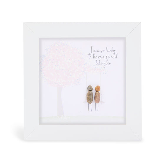 These small white shadow box frame gifts are made with a 4-inch white shadow box frame with a plexiglass insert, helping it be less fragile in the post and around the home. You can also easily take them apart to clean the inside of the glass or frame if you need to. They come individually boxed for added protection during shipping.

This white shadowbox framed pebble art print 2 people walking in a field with a tree.&nbsp;It reads I am so lucky to have a friend like you.