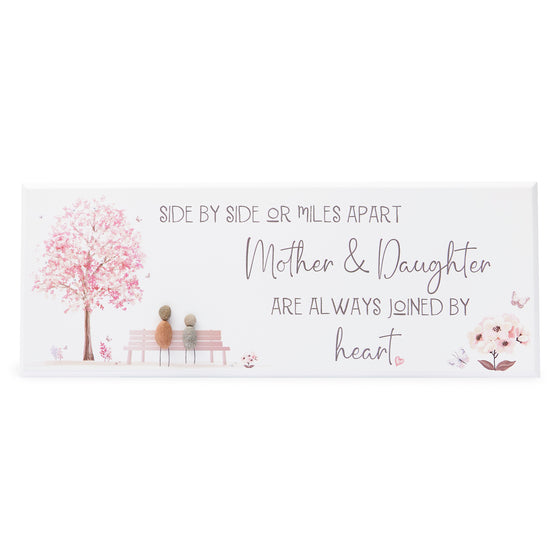 These wood plaques have all been painted white prior to their individual designs being painted on with the pebble art. They measure 32cm (L) x 12cm (W) x 1cm (D) and can be hung on the wall if desired.&nbsp;

This beautiful wood plaque depicts 2 people sitting on a bench under a tree and it reads Side by side or miles apart Mother's &; Daughters are always joined by heart.