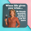 Funny woman's coaster; featuring an elegantly dressed lady, drinking wine and smiling; bold white text on a blue backround reads 'when life gives you wine, be bloody greatful, drink it and then ask for more'; by Dean Morris.