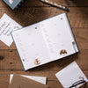 A rustic, navy address and birthday book featuring a large highland cow with 2 small, baby highland cows. Golden text at the top of the card reads "Address and birthday book" by Wrendale Designs.